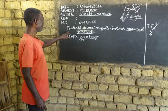 Un enseignant explique le calcul des intérêts mensuels lors d’un cours dans le village de Bekombo en République démocratique du Congo