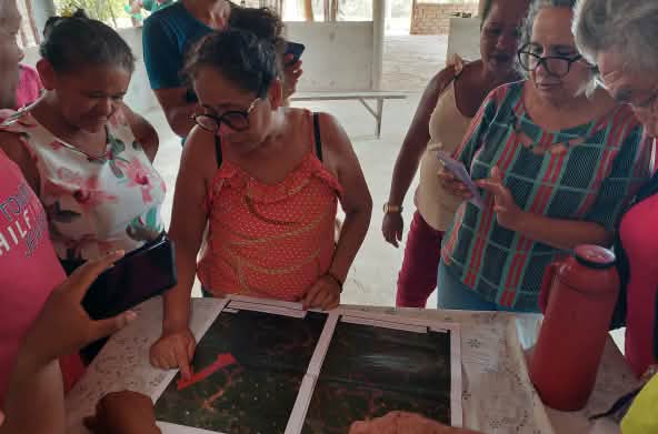 Un groupe de six femmes examine deux plateaux sur lesquels sont disposées des graines