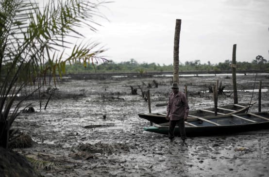 Un homme se tient debout dans le lit d’une rivière polluée par le pétrole dans le delta du Niger