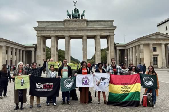 Un groupe de 11 personnes avec des banderoles devant la porte de Brandebourg à Berlin.