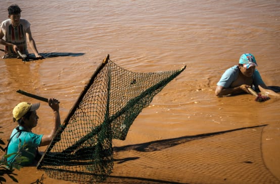 Trois hommes pêchent dans les eaux brunes d’un lac