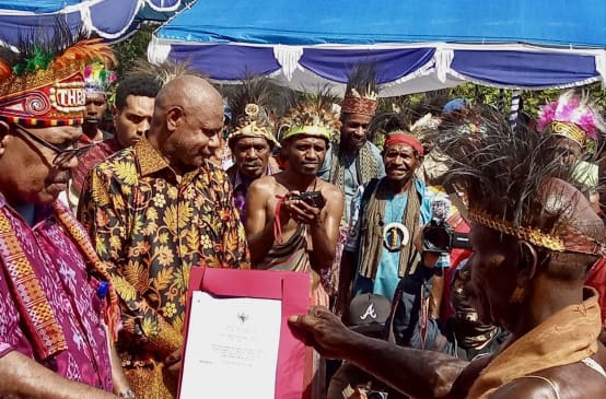 Un groupe de Papous en vêtements traditionnels tenant un certificat