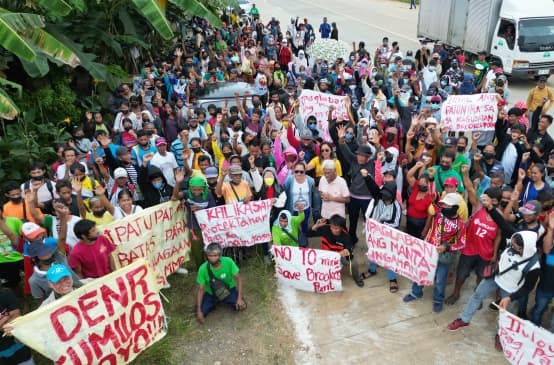 Des femmes et des hommes forment un barrage humain devant le site d’extraction d’Ipilan Nickel Corporation