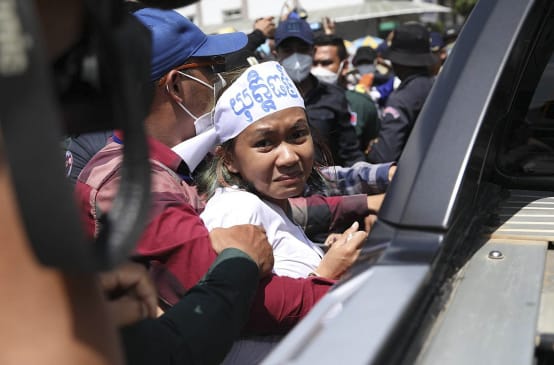 Apeurée, une jeune activiste cambodgienne nous regarde au moment d’entrer dans un véhicule de police