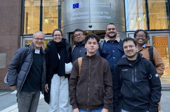 Photo de groupe de 7 personnes devant l’entrée du bâtiment de la Direction générale des partenariats internationaux à Bruxelles