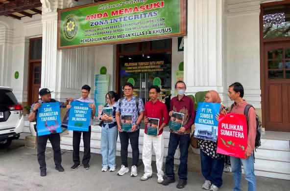8 personnes tenant des pancartes devant un palais de justice