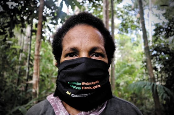 Papoue portant un masque noir sur lequel est écrit : « Protégeons la forêt. La forêt nous protège. »