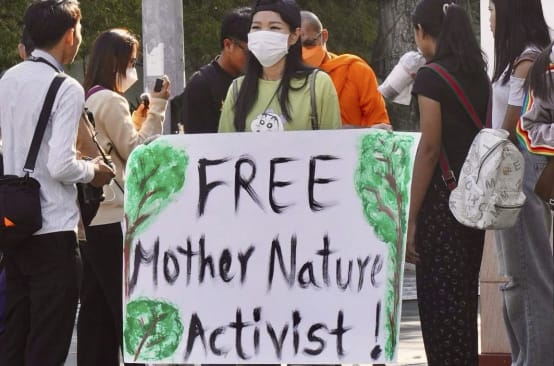 Une militante tient une grande pancarte sur laquelle on peut lire « Free Mother Nature Activist ! »