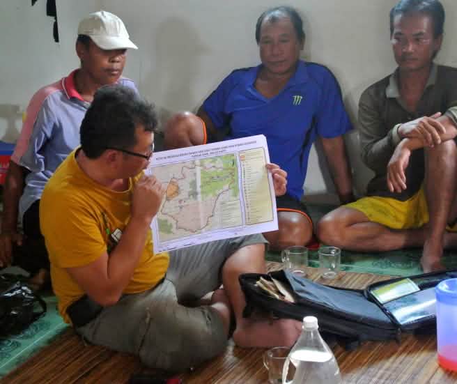 Il explique aux villageois de quelle manière ils peuvent s’opposer aux bûcherons (© Rettet den Regenwald / Mathias Rittgerott) Matek (SADIA) tient une carte de la déforestation illégale