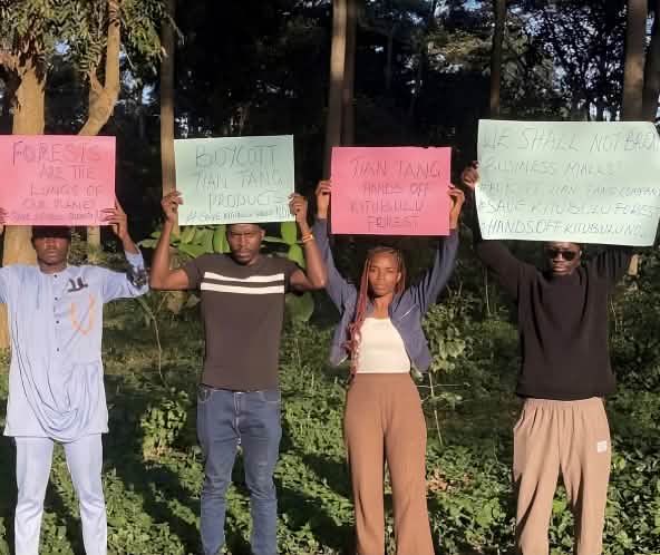 des hommes et des femmes brandissant des pancartes devant une forêt tropicale.