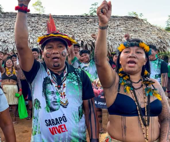 Deux femmes et un homme du peuple indigène Ka’apor les poings levés