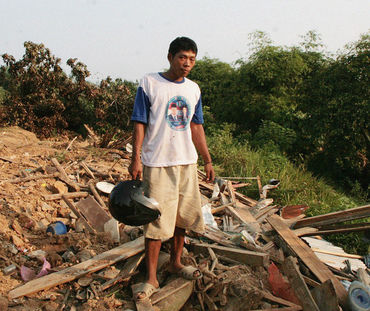 Un paysan se tient devant son village en ruines