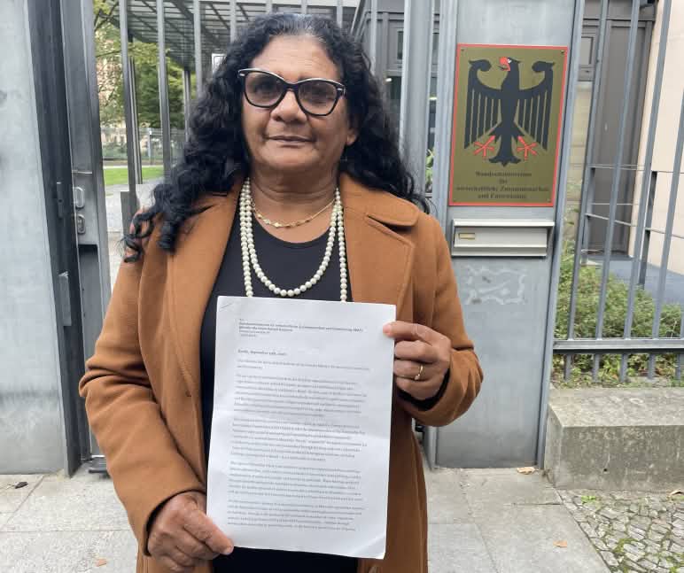 La femme quilombola Marli Borges tenant une lettre devant l’entrée grillagée du Ministère fédéral de la Coopération économique et du Développement (BMZ)