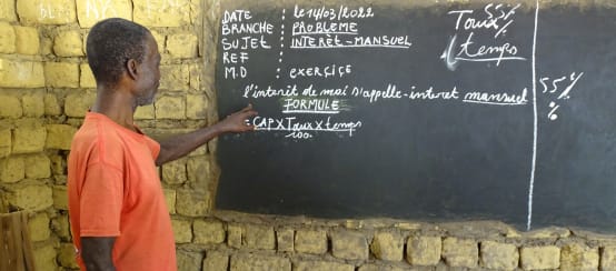 Un enseignant explique le calcul des intérêts mensuels lors d’un cours dans le village de Bekombo en République démocratique du Congo