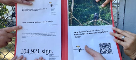 Des mains de différentes personnes sur notre pétition devant l'ambassade de la RDC à Berlin