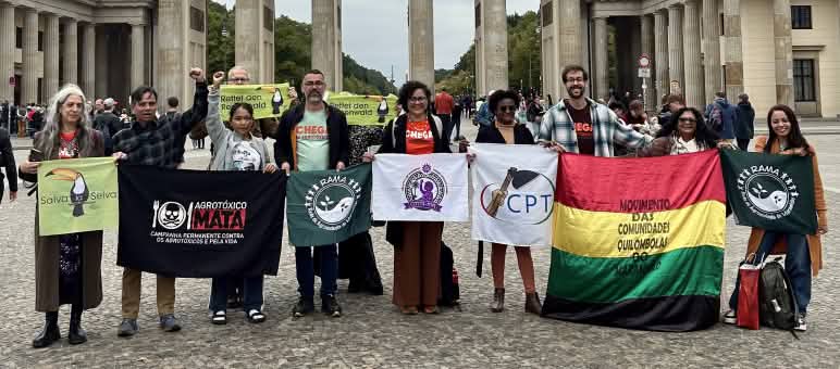 Un groupe de 11 personnes avec des banderoles devant la porte de Brandebourg à Berlin.