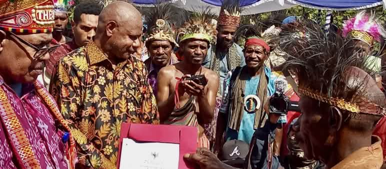 Un groupe de Papous en vêtements traditionnels tenant un certificat