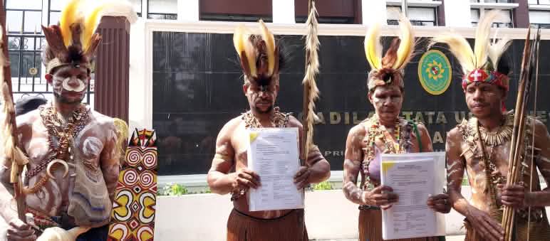 Quatre Papous en tenue traditionnelle devant le tribunal