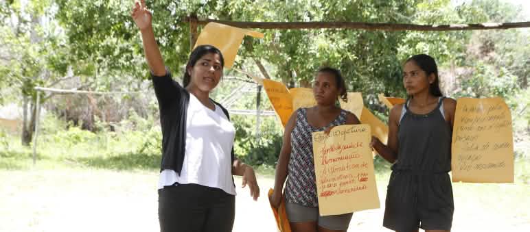 Trois femmes brandissent des pancartes peintes à la main