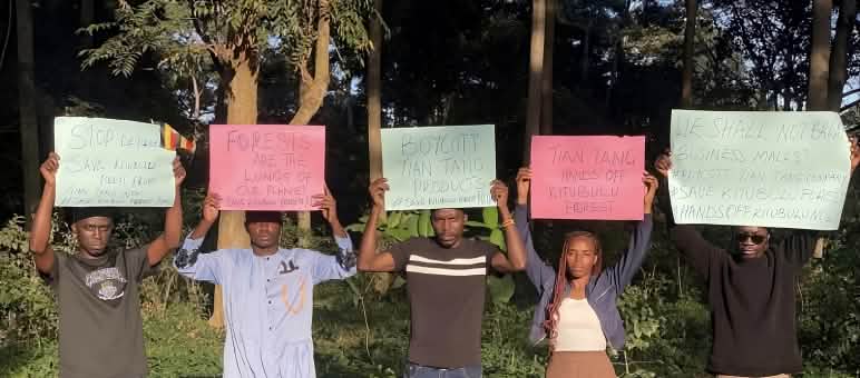 des hommes et des femmes brandissant des pancartes devant une forêt tropicale.