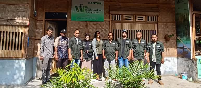Sauvons la forêt a rencontré ses partenaires d’Aceh Wetland Forum sur le terrain en 2023 Photo de groupe de la biologiste Rita Glaus de Sauvons la forêt entourée de l’équipe de l’organisation AWF devant son bureau, un édifice en rotin et bambou