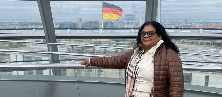 La femme quilombola Marli Borges sous la coupole de verre du Bundestag allemand, avec le drapeau fédéral en arrière-plan.