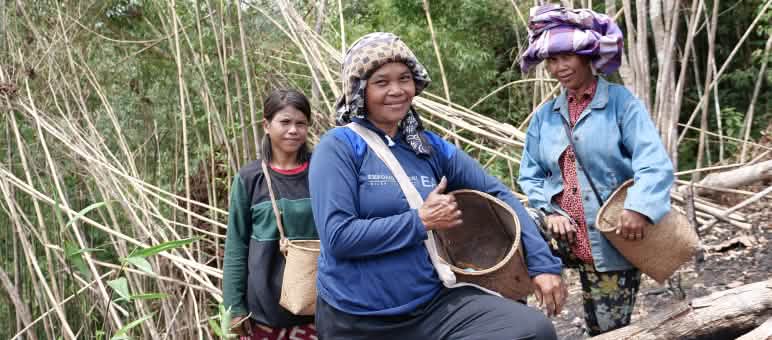 Trois femmes du peuple Dayak avec des paniers pour la cueillette sourient à la caméra