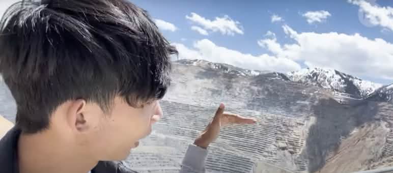 Un jeune homme regarde une grande mine à ciel ouvert