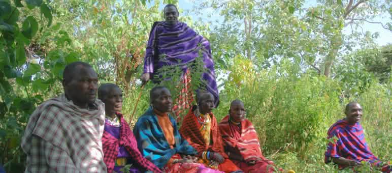 Un groupe d’hommes Masaï est assis dans l’herbe, vêtus de couvertures colorées