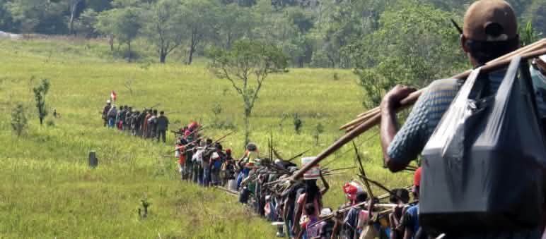File indienne d’indigènes qui traversent une savane en allant à la chasse,