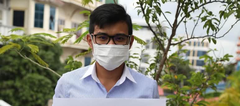 Un jeune homme brandit une affiche avec les photos des 6 militants de Mother Nature emprisonnés
