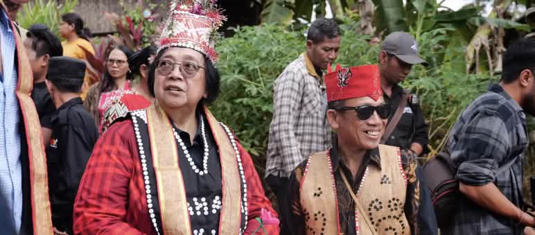 Femme vêtue d’une veste rouge et un homme en costume traditionnel dayak