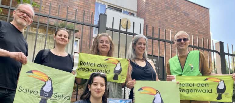 6 personnes posent devant la grille du bâtiment de l’ambassade du Cambodge à Berlin, tenant des bannières de l’association "Rettet den Regenwald"