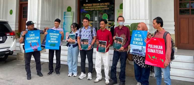 8 personnes tenant des pancartes devant un palais de justice