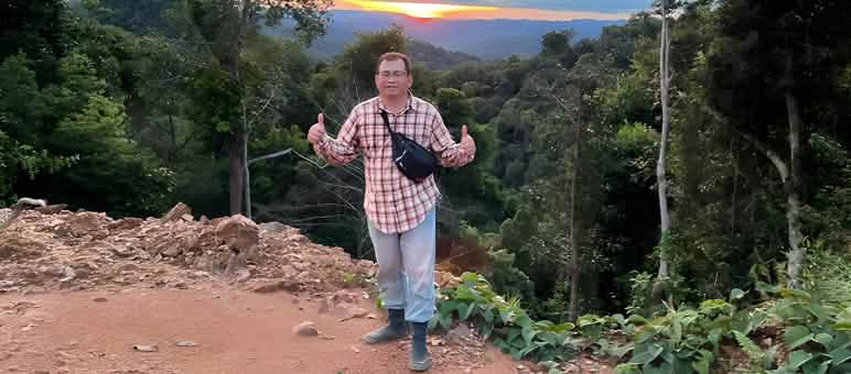 Notre partenaire Matek Geram contribue activement à la sauvegarde de la forêt tropicale L’écologiste Matek Geram montre les deux pouces devant un paysage forestier