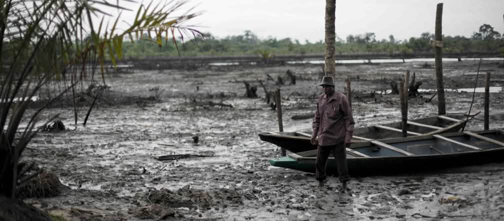 Un homme se tient debout dans le lit d’une rivière polluée par le pétrole dans le delta du Niger