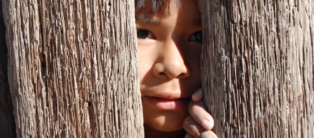 Un enfant regarde entre deux planches de bois