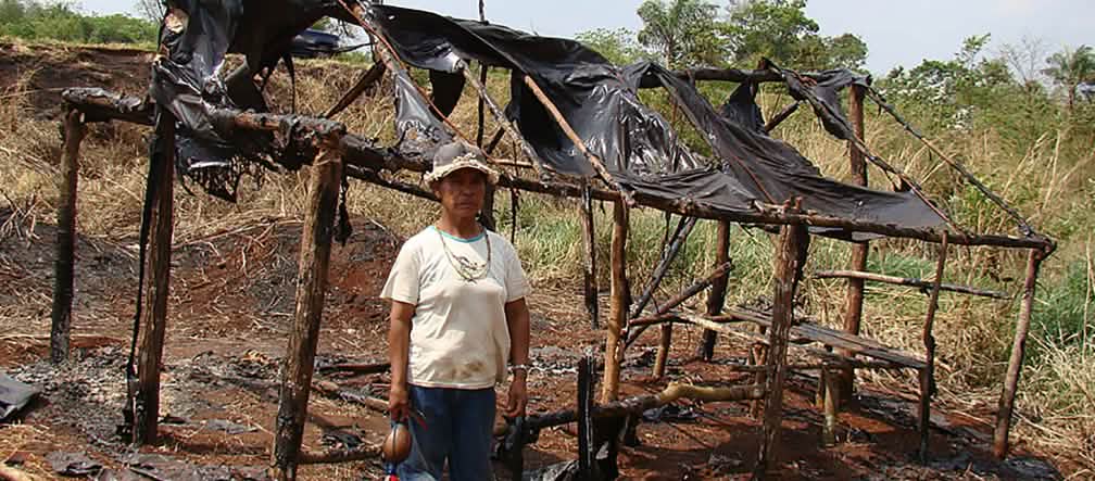 Damiana, Guaraní-Kaiowá et guide spirituelle Apyka'y, devant une hutte calcinée pendant les expulsions