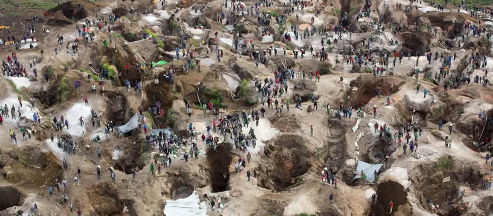 Vue aérienne au-dessus d’une mine, avec trous profonds, en partie remplis d’eau, entre lesquels se trouvent de nombreuses personnes