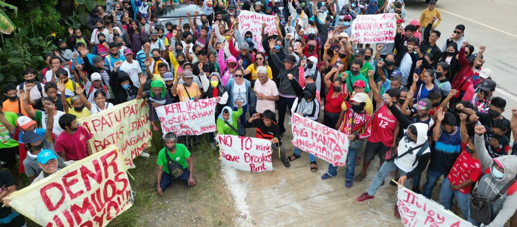 Des femmes et des hommes forment un barrage humain devant le site d’extraction d’Ipilan Nickel Corporation