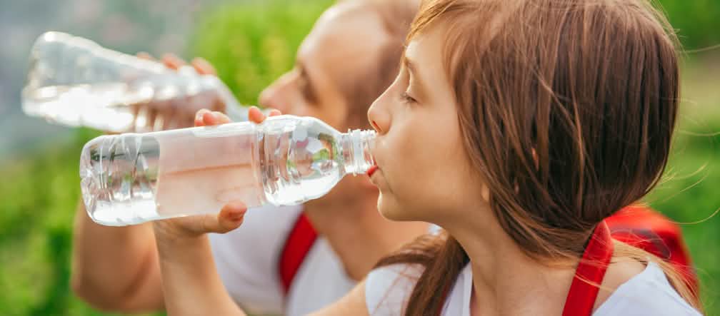 L’eau embouteillée dans du plastique n’est pas forcément saine Une jeune fille en train de boire de l’eau dans une bouteille en plastique jetable PET