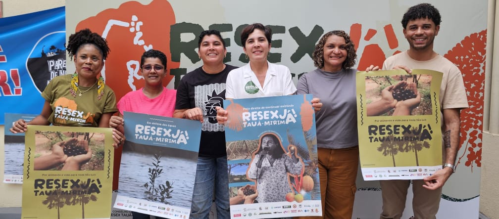 Six personnes brandissent des pancartes avec différents motifs et l’inscription « Resex Tauá-Mirim maintenant ! » en portugais