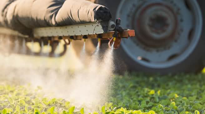 Le glyphosate peut et doit être interdit par les gouvernements des pays européens Un tracteur est en train d'épandre des pesticides sur un champ dans l'Union européenne