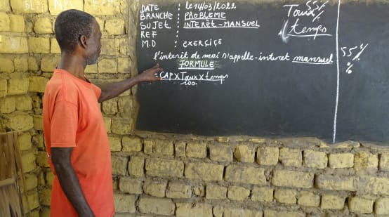 Un enseignant explique le calcul des intérêts mensuels lors d’un cours dans le village de Bekombo en République démocratique du Congo