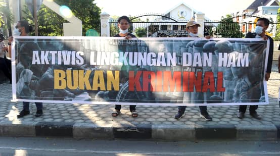 Des activistes de JATAM montrent une banderole avec écrit en indonésien « Les défenseurs de l’environnement et des droits de l’homme ne sont pas des criminels » pour exprimer leur solidarité avec Sauvons la forêt