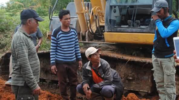 Wardian se tient devant un bulldozer et discute avec les ouvriers