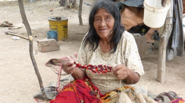 Une indigène Manjui assise sur le sol travaille un tissu en fibres végétales