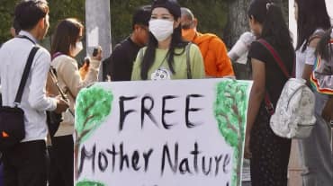 Une militante tient une grande pancarte sur laquelle on peut lire « Free Mother Nature Activist ! »