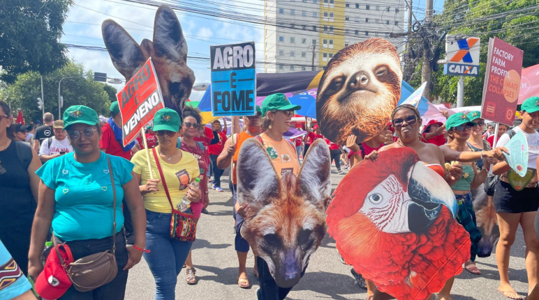 Des personnes manifestent en portant de grandes affiches représentant des têtes d’animaux