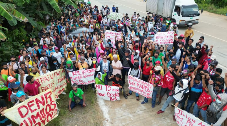 Des femmes et des hommes forment un barrage humain devant le site d’extraction d’Ipilan Nickel Corporation